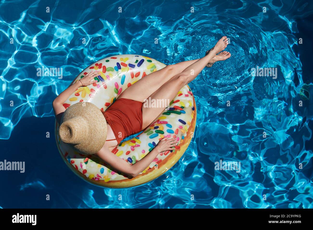 Young woman on inflatable donut ring in swimming pool, summer vacation concept Stock Photo