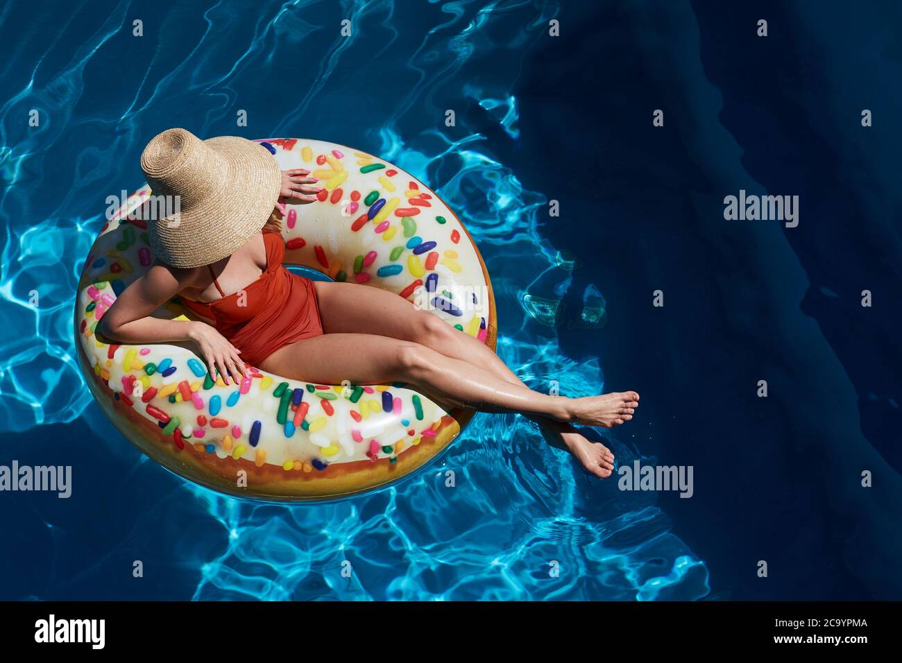 Young woman on inflatable donut ring in swimming pool, summer vacation concept Stock Photo