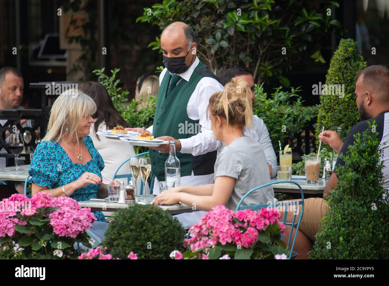 Diners eat outside the Ivy Market Grill, in London, one of the participating restaurants where diners will be able to enjoy half-price meals, starting on Monday as the Government kick-starts its August scheme aimed at boosting restaurant and pub trade following the lockdown. Stock Photo