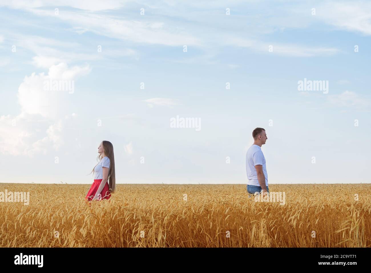 couple standing back to each other in wheat field. Divorce. Stock Photo