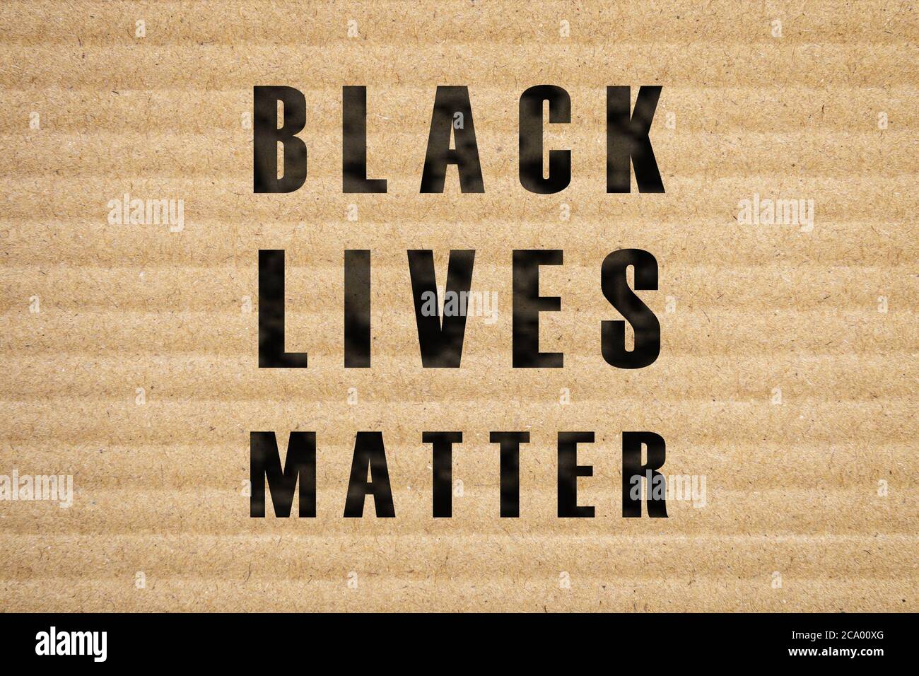 Black Lives Matter slogan on cardboard banner. Corrugated carton picket sign, placard for demonstrations. Protest marches and riots against police vio Stock Photo