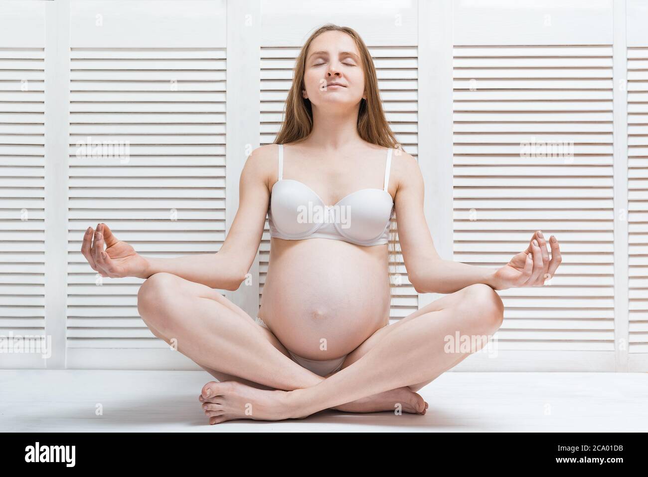 Beautiful young pregnant woman meditating. pregnant female doing yoga in home Stock Photo