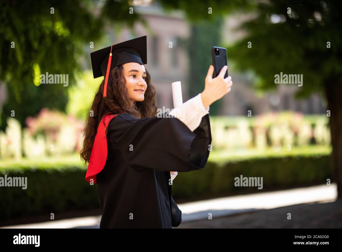 graduated-woman-in-graduation-hat-and-gown-outdoors-make-joint-selfie