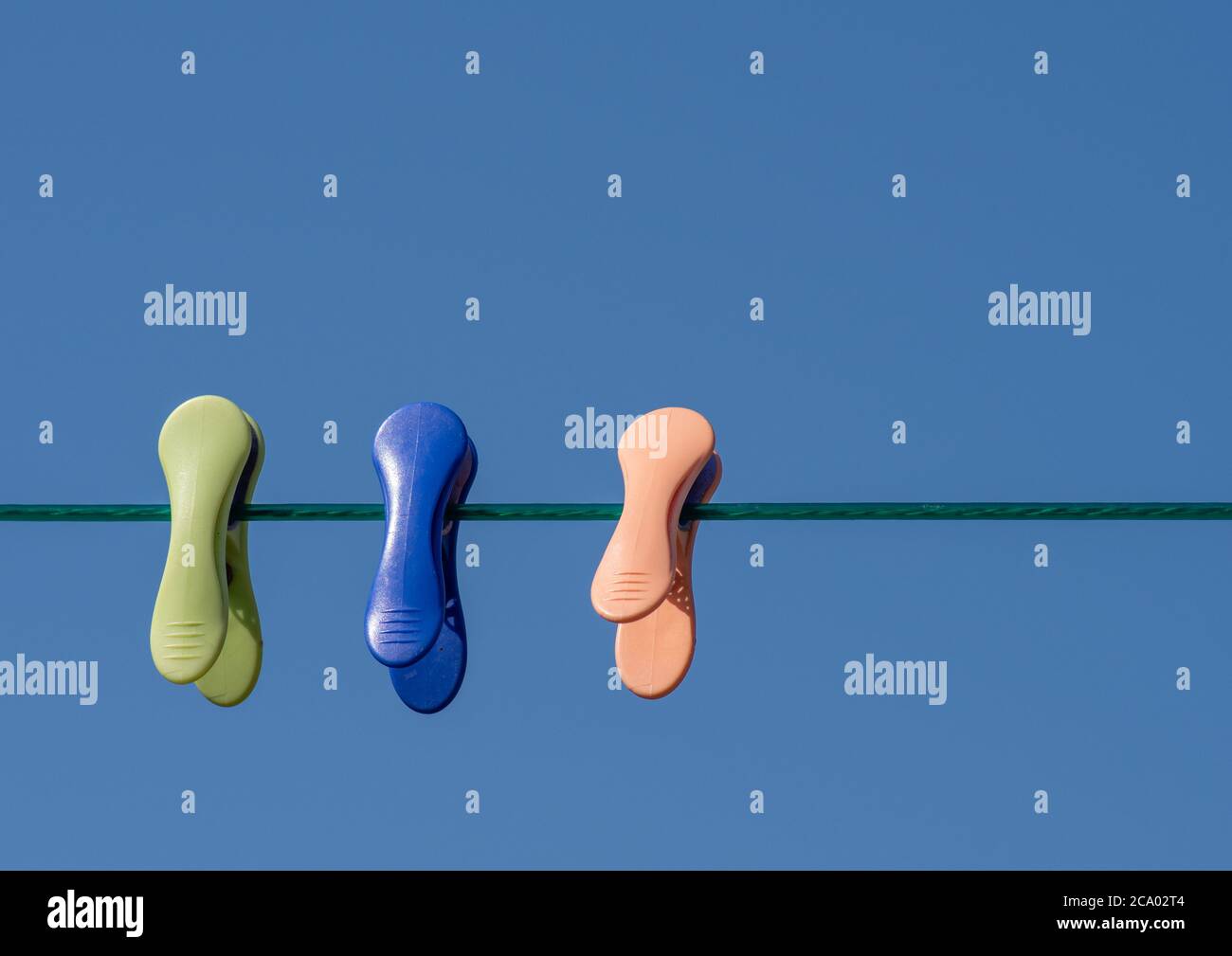 Coloured cloths pegs on a washing line with clear blue sky background Stock Photo