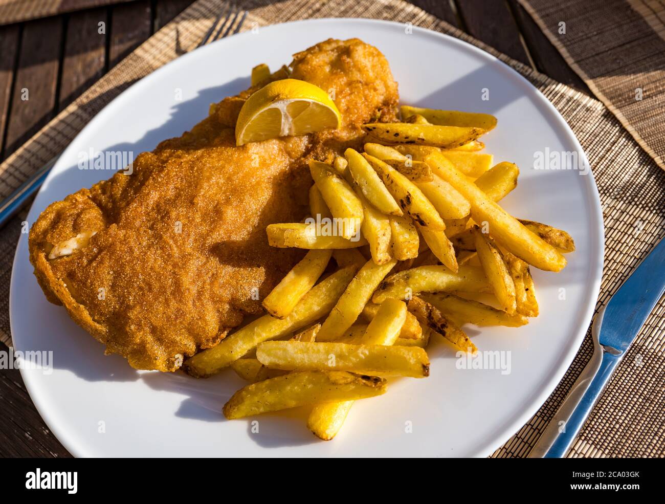 Haddock fish and chips or fish supper on plate in Summer sunshine with lemon, Scotland, UK Stock Photo