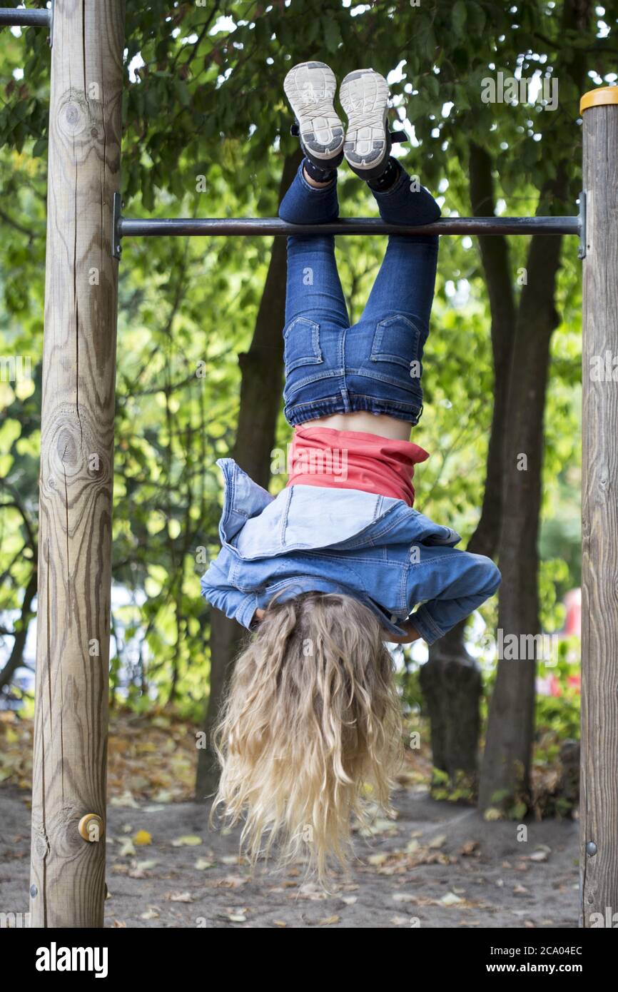 Girl (10) hangs upside down on horizontal bar, Kiel, Schleswig-Holstein, Germany Stock Photo
