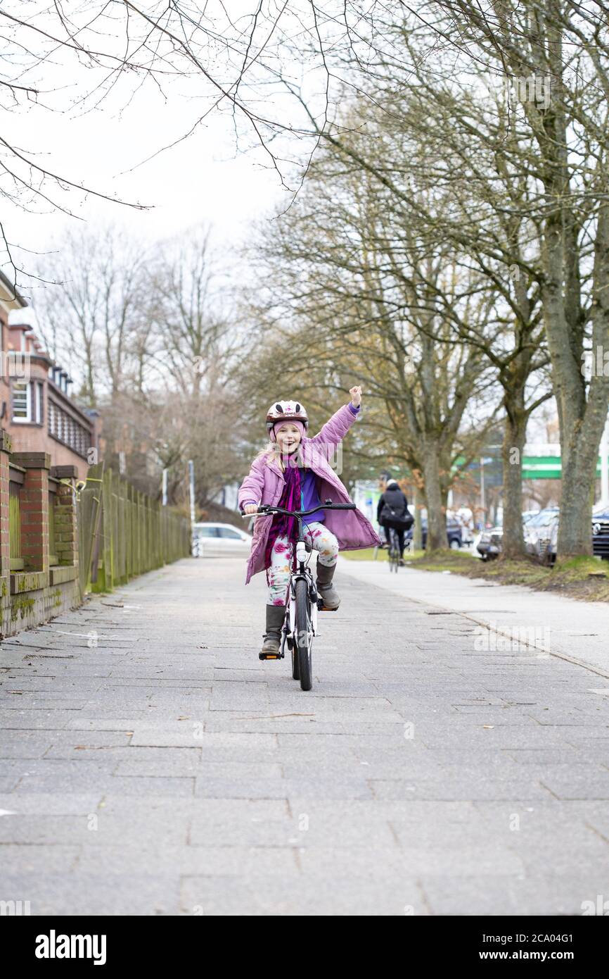 Girl (8) safely rides a bicycle on a sidewalk, Kiel, Schleswig-Holstein, Germany Stock Photo