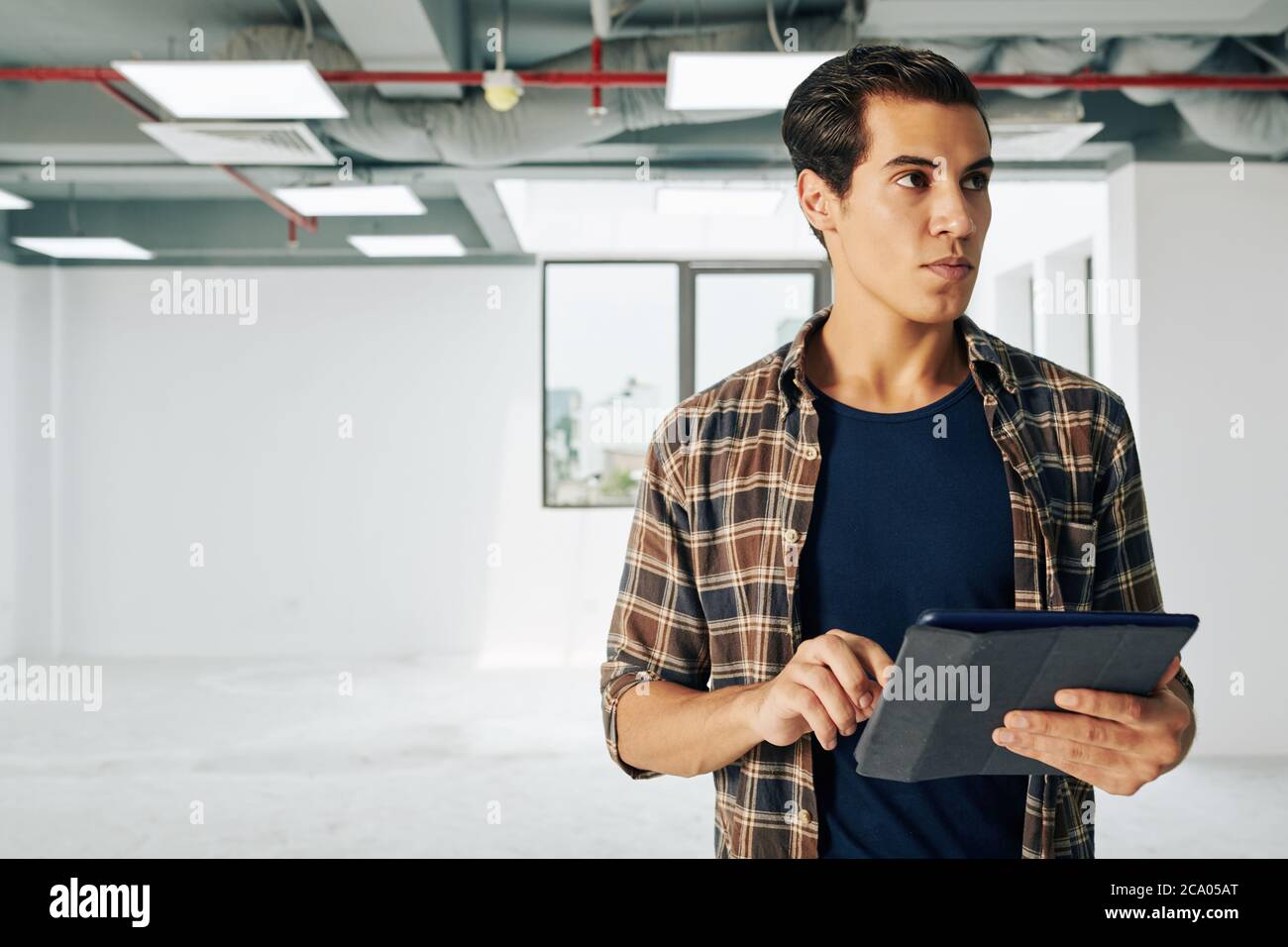 Young real estate manager visiting new building and filling information in database on tablet computer Stock Photo