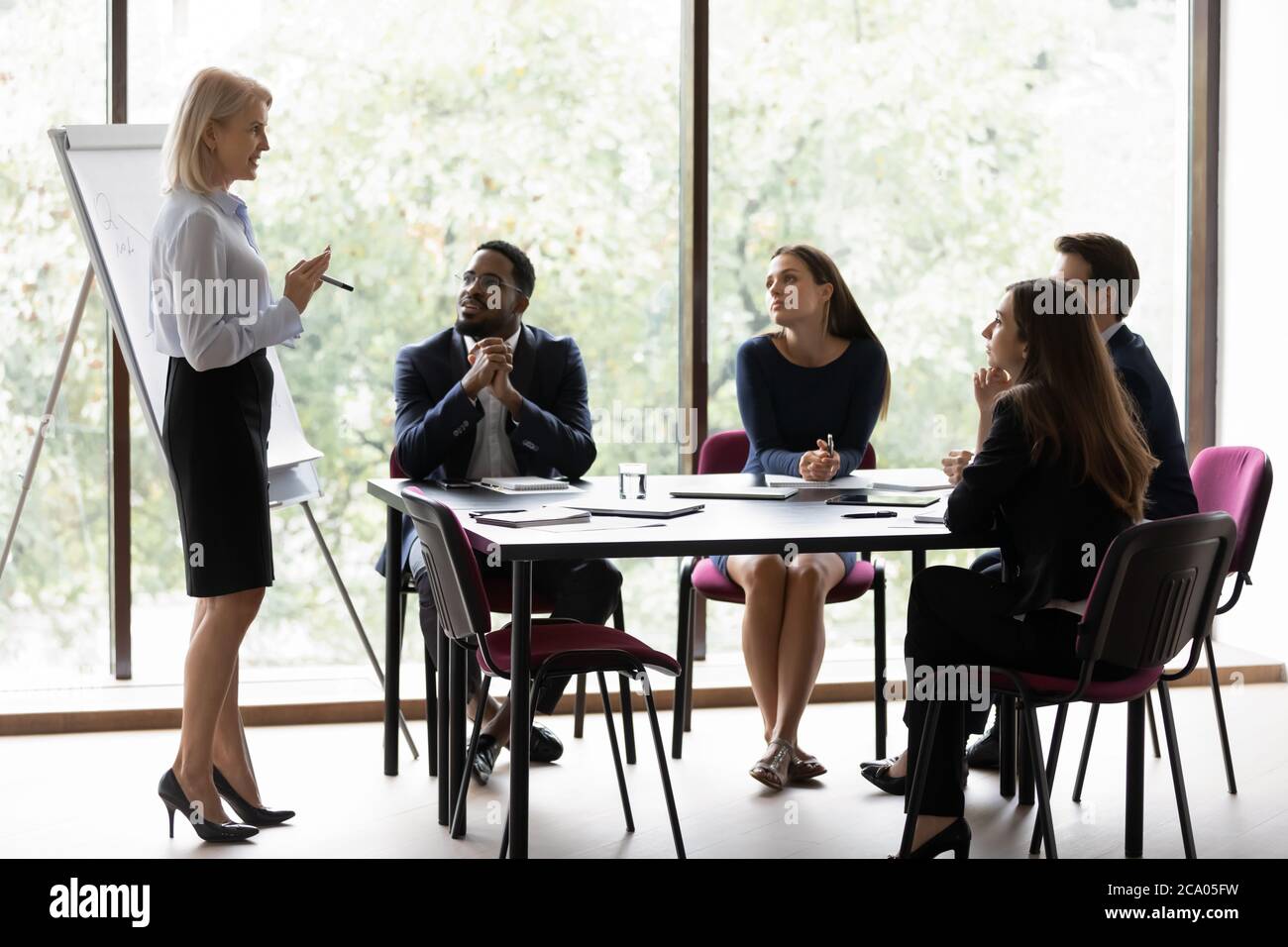 Multiethnic people participating at seminar educational meeting sit in boardroom Stock Photo