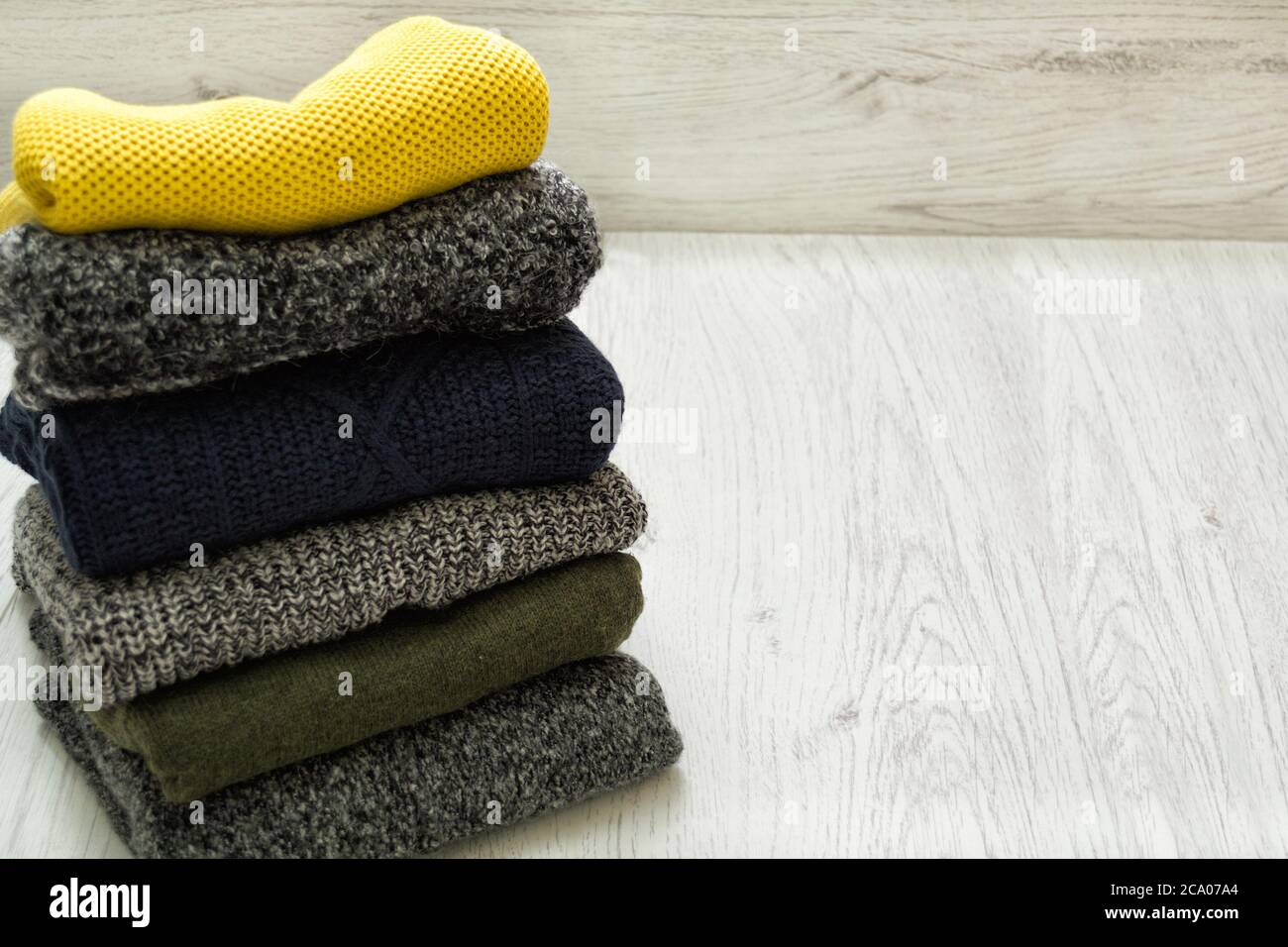 Stack of sweaters on a wooden background. Fashionable concept. Stock Photo