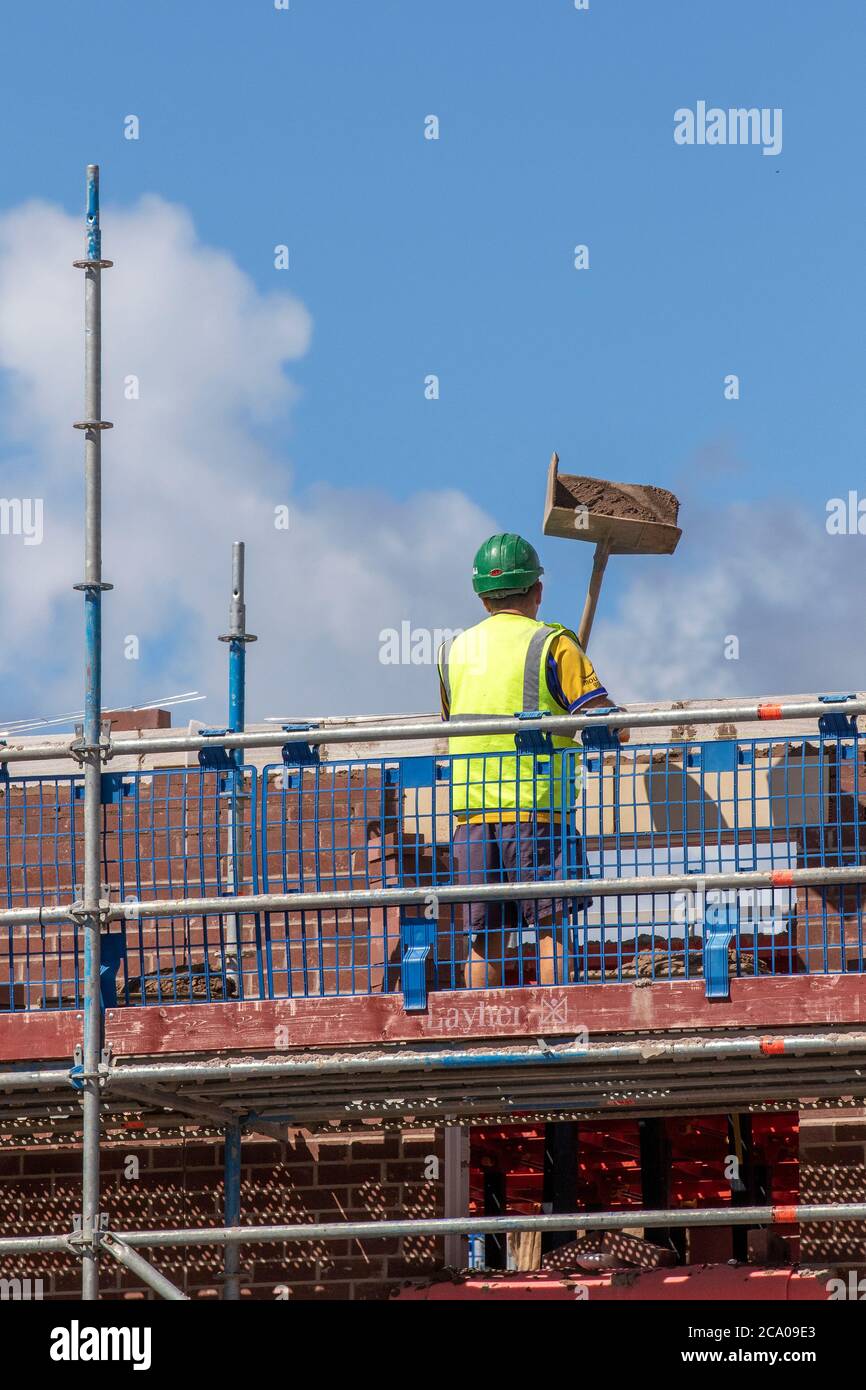 Builders working in Tarleton, Lancashire.  UK Weather. Hot summer sun for new build housing estate development in the new Persimmon housing Estate in Douglas Gardens. A major development that may be put on hold depending on the severity of the impending recession.  Contractions are expected to be sharpest in private housing (-42 per cent), commercial and private housing repair, maintenance and improvement , these are the sectors that are most closely linked to consumer and business confidence, likely to be significantly dented by fading job security and rising unemployment. Stock Photo