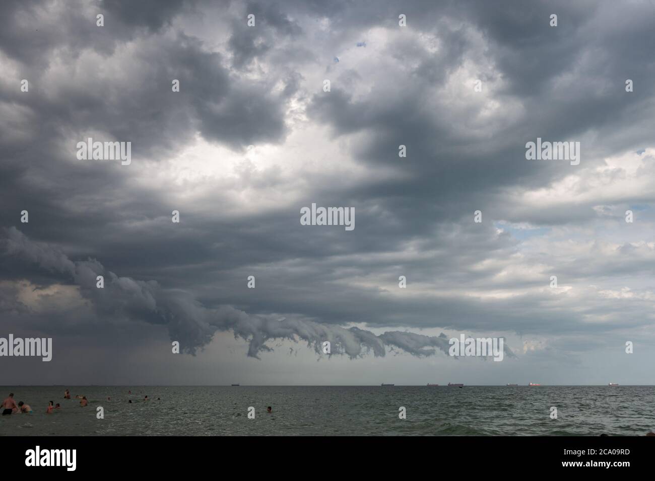 Dramatic clouds over the sea and the beach with people Stock Photo - Alamy