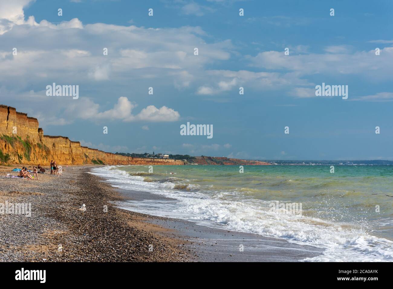 Wild beach in the village of Nikolaevka Crimea on June 14, 2020. Beautiful summer landscape with stormy sea. Bright sun and blue sky. Clay high banks. Stock Photo