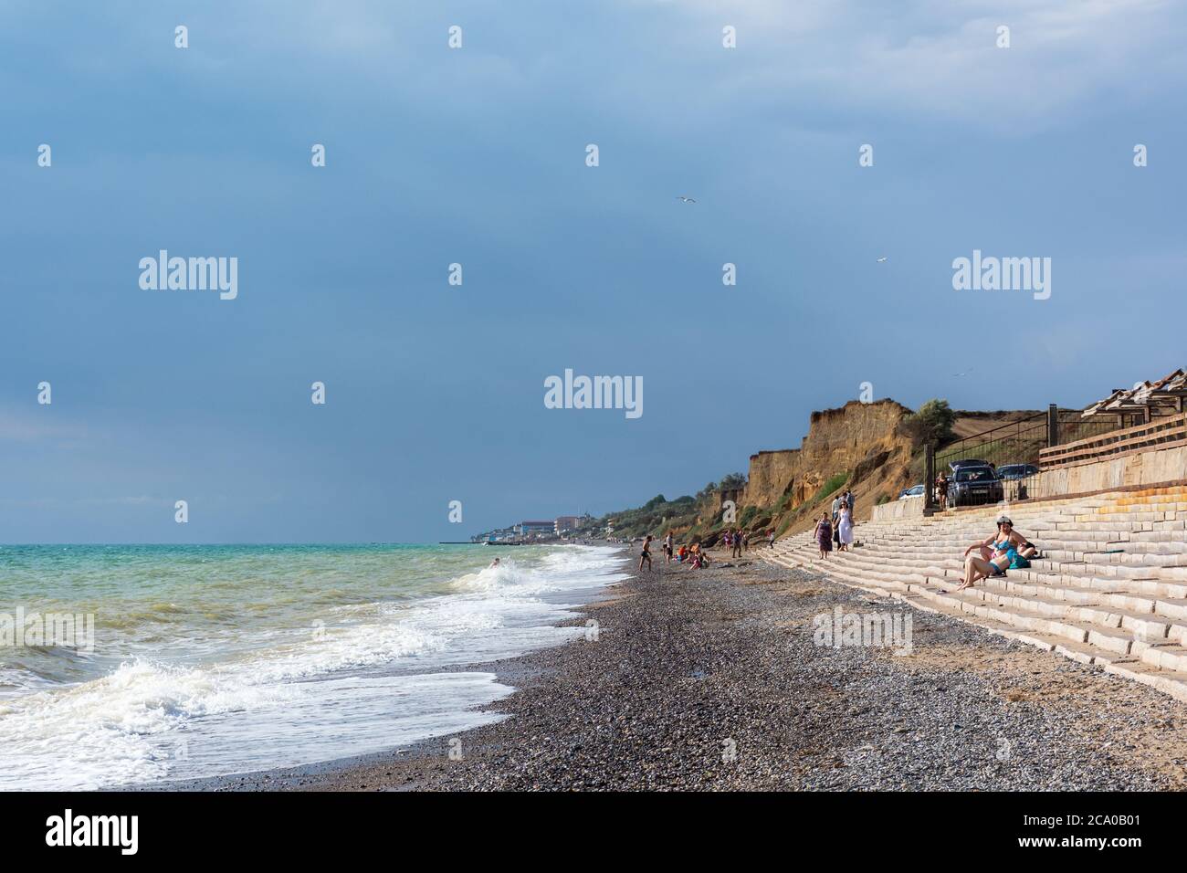 Wild beach in the village of Nikolaevka Crimea on June 14, 2020. Beautiful summer landscape with stormy sea. Bright sun and blue sky. Clay high banks. Stock Photo