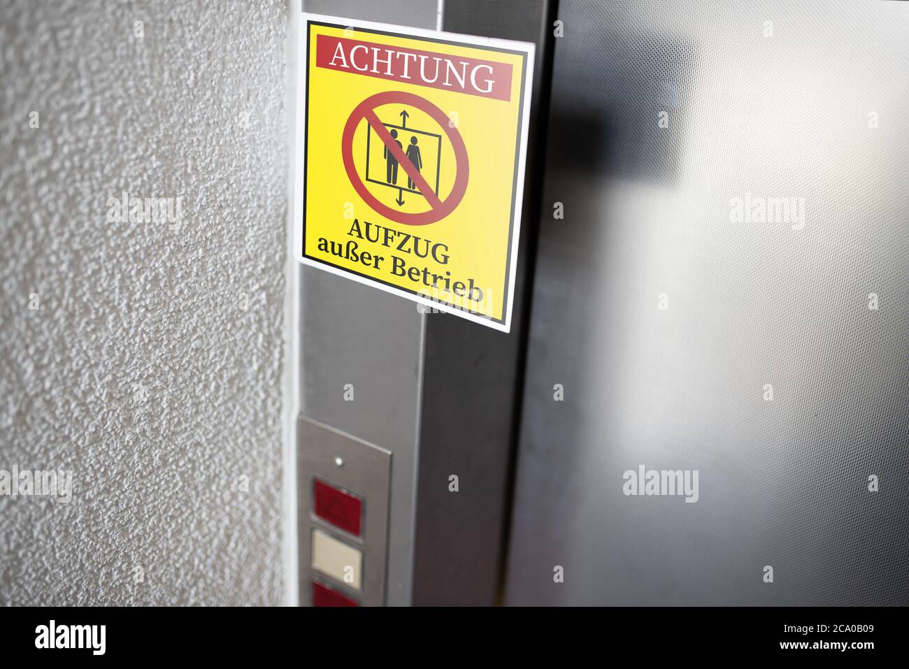 yellow service sign with German text for ELEVATOR OUT OF SERVICE attached to elevator door, digital composite Stock Photo