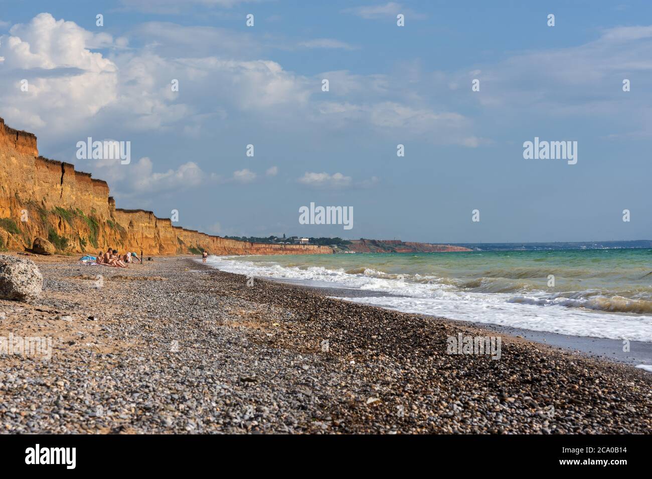 Wild beach in the village of Nikolaevka Crimea on June 14, 2020. Beautiful summer landscape with stormy sea. Bright sun and blue sky. Clay high banks. Stock Photo