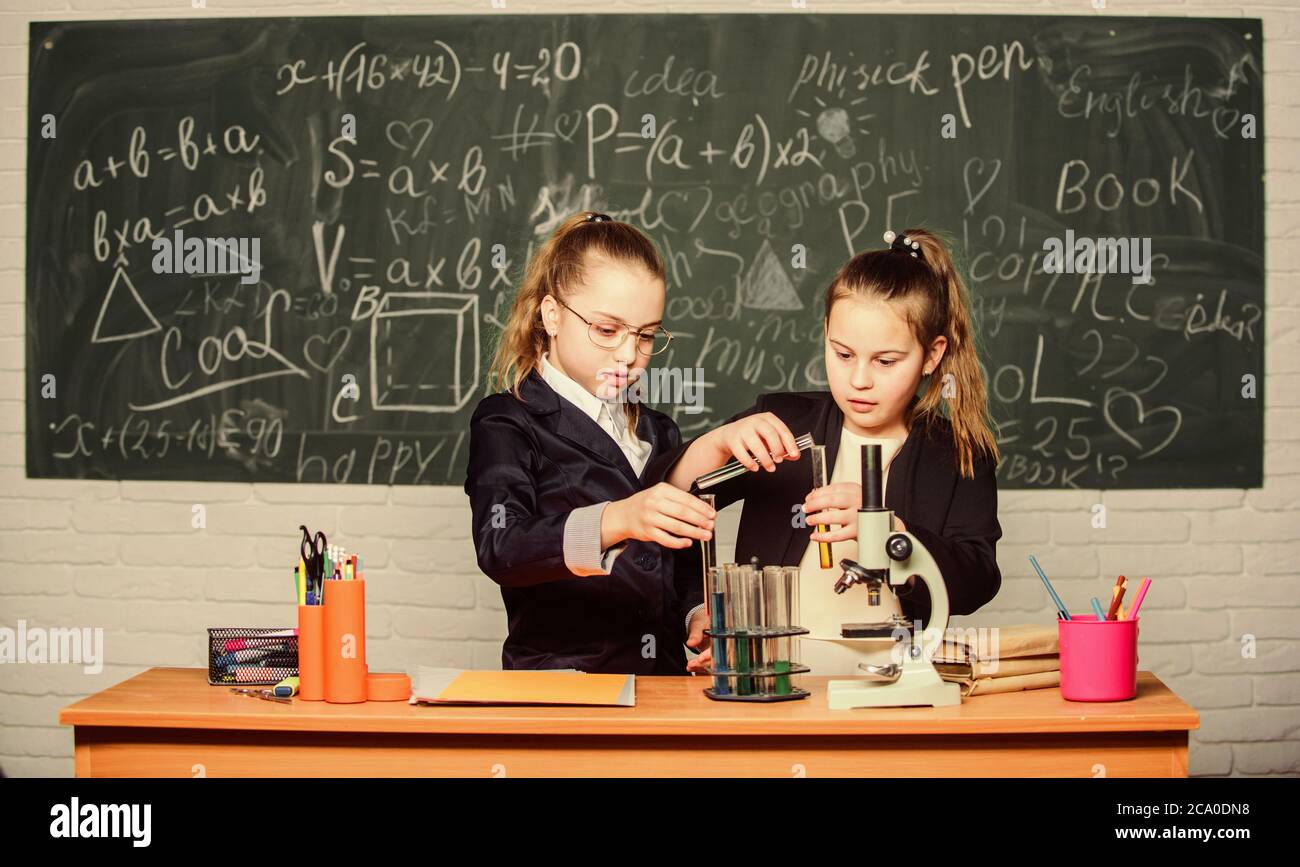 Chemistry research. Children using microscope. Little girls in school lab. Microscope. Biology lesson. Checking the results. Little scientist work wit Stock Photo