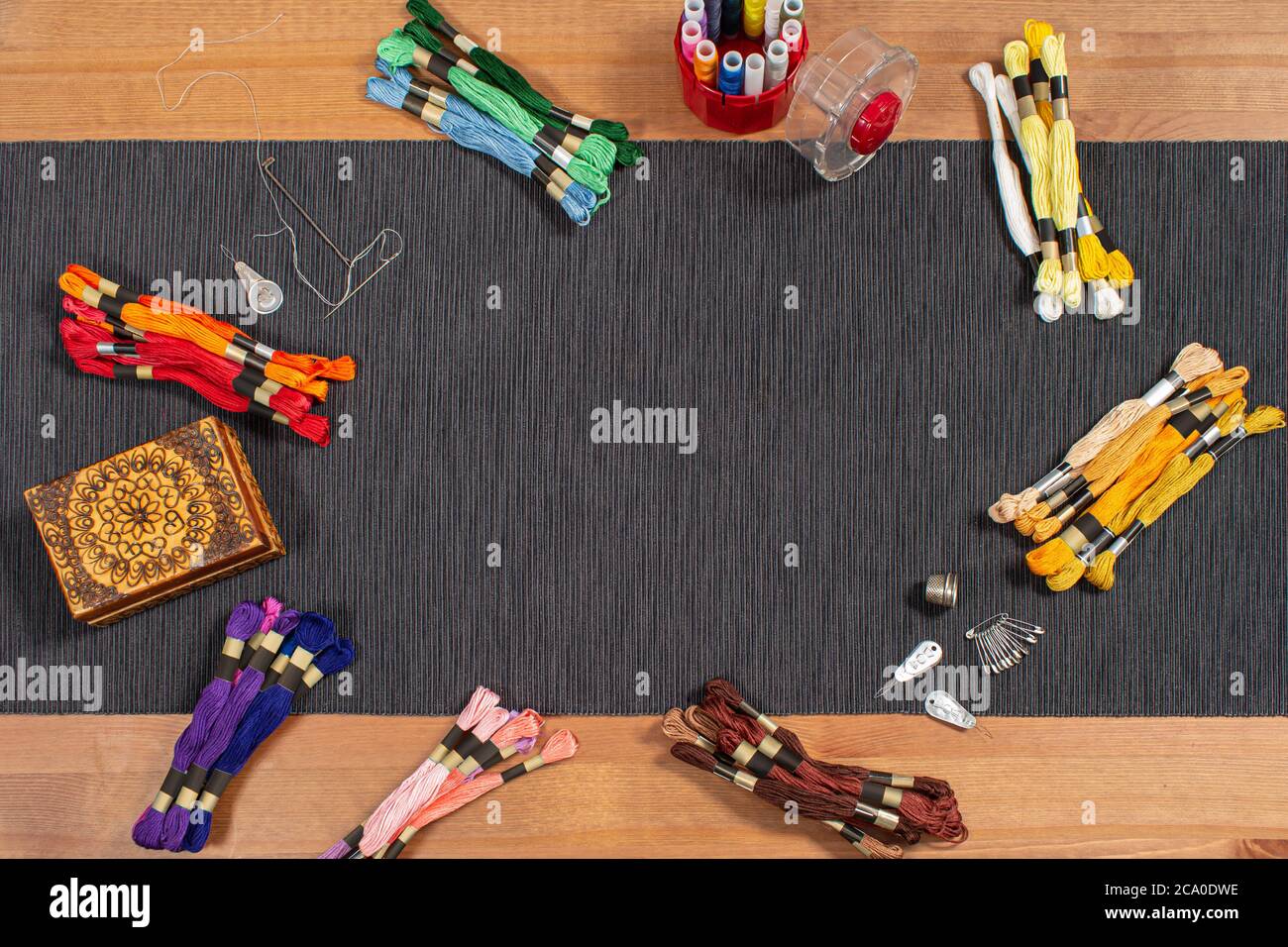 Various colored mouline threads, yarns, threads lie on the table with accessories for needlework and sewing. Place for text inside. Stock Photo