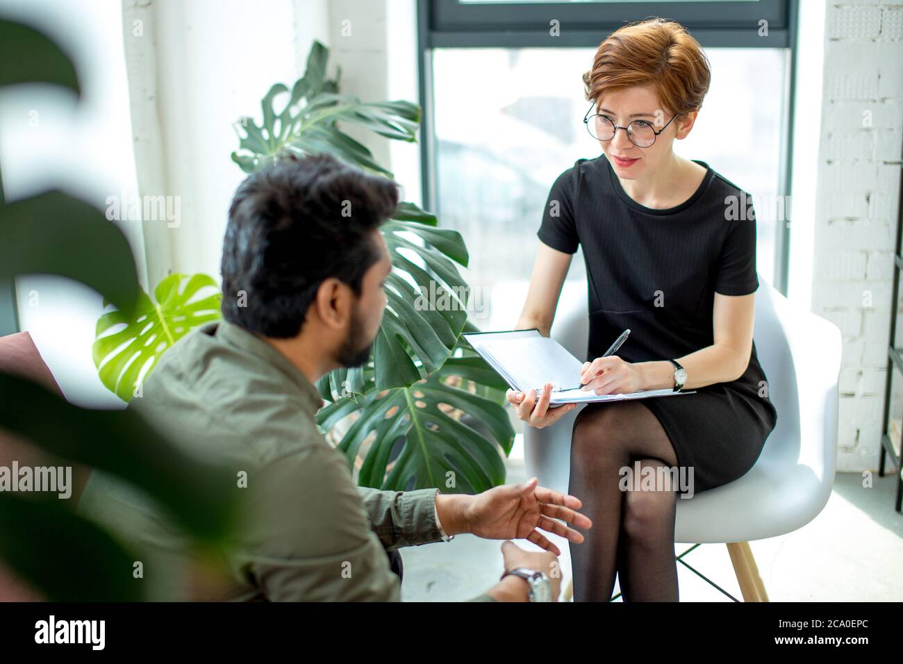 psychotherapist consulting man, asking questions, interviewing man sitting on sofa. psychologist