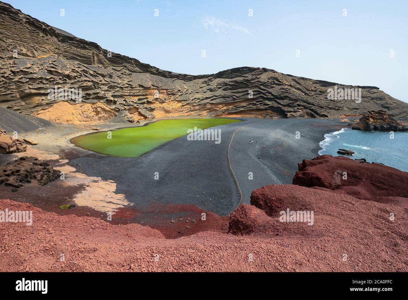 Lago Verde ('Green Lake') in El Golfo, Lanzarote, Canary Islands, Spain. Colorful landscape with black sand beach, dark volcanic rocks and red earth. Stock Photo