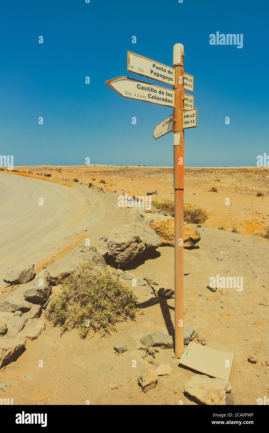 Desert road sign pointing towards Punta de Papagayo and Castillo de las Coloradas, seen near Playa Blanca, Lanzarote, Canary Islands, Spain. Stock Photo