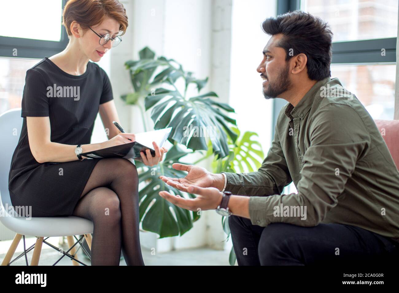 psychotherapist consulting man, asking questions, interviewing man sitting on sofa. psychologist