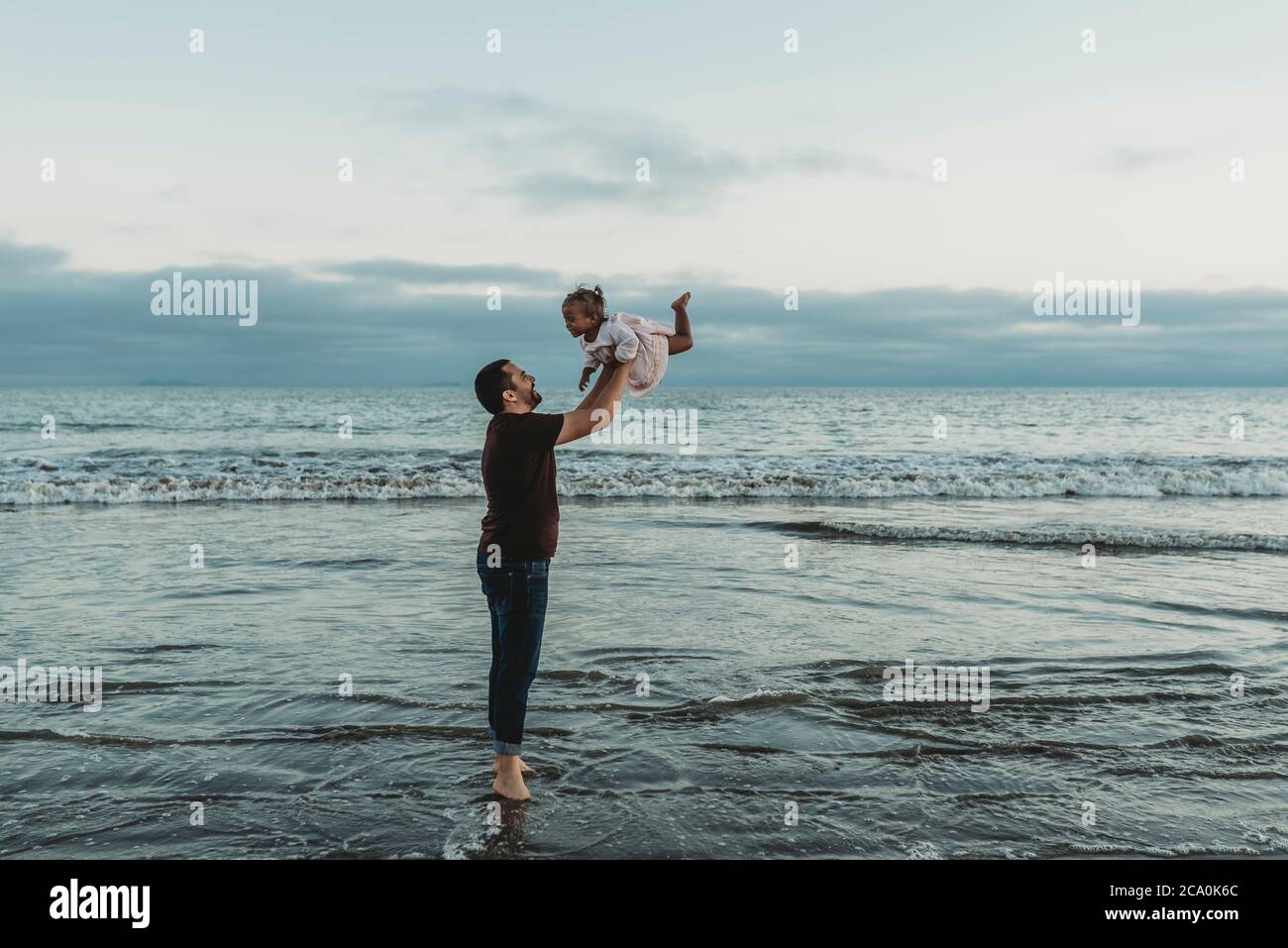 Dad throwing his daughter in air in the ocean Stock Photo Alamy