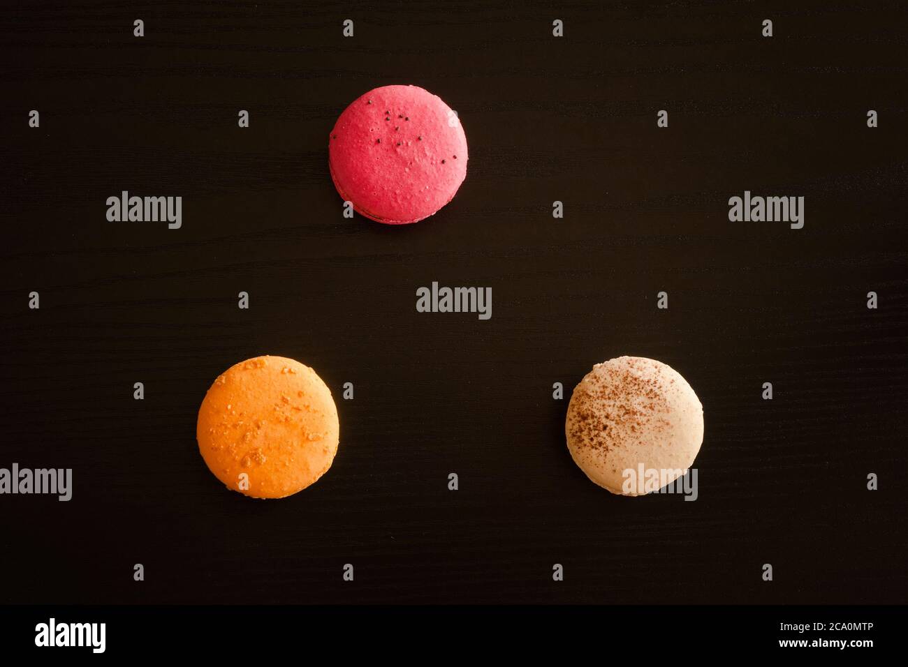 Three multicolored macarons on a black background Stock Photo