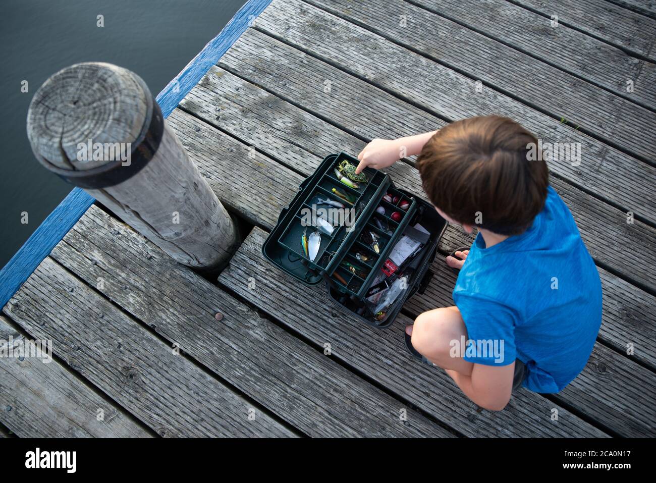 https://c8.alamy.com/comp/2CA0N17/young-boy-looking-through-a-fishing-tackle-box-on-a-wooden-dock-2CA0N17.jpg