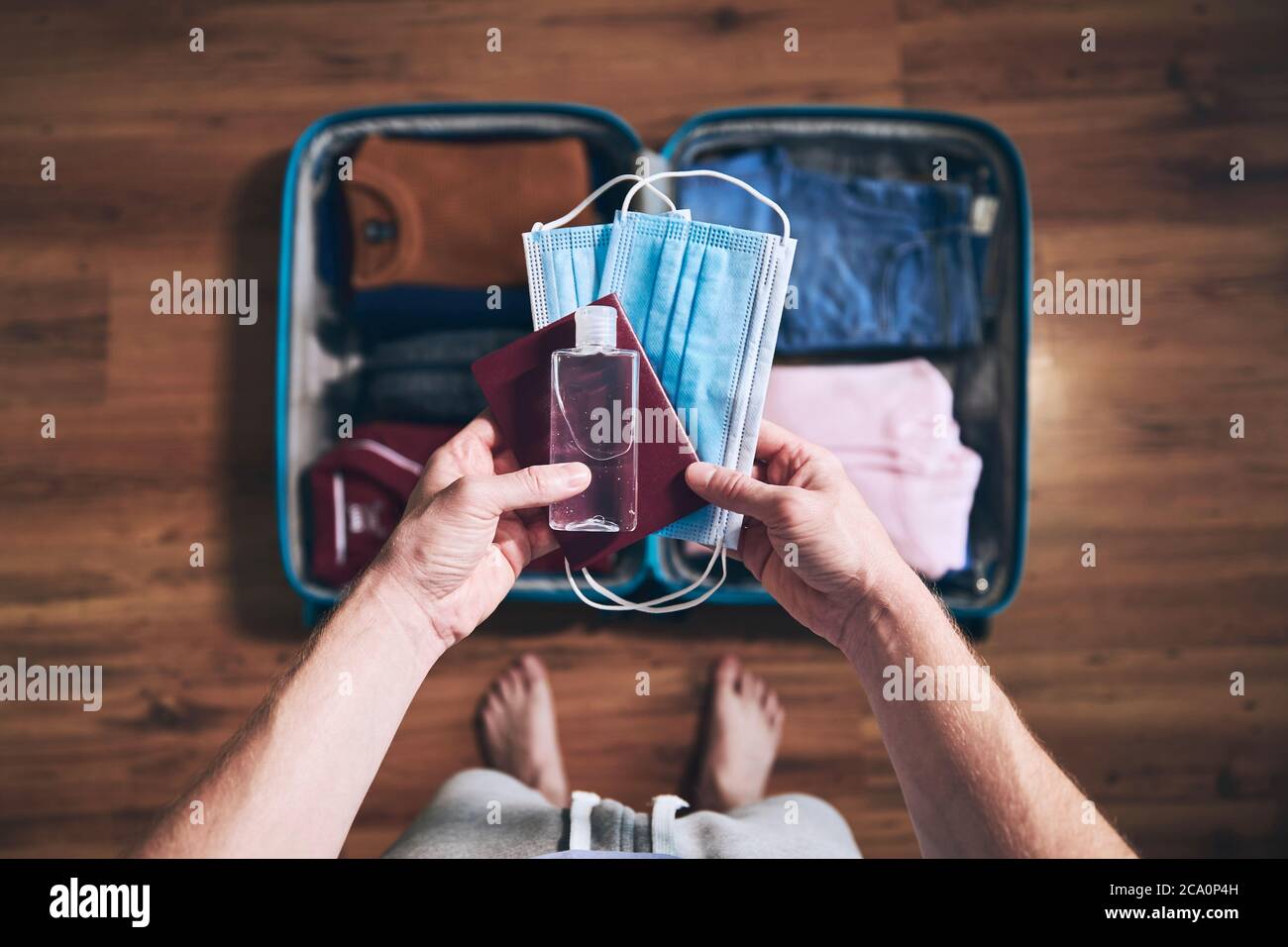 Preparing for travel in new normal. Man packing passport, face masks and hand sanitizer. Themes personal protection and flight rules during coronaviru Stock Photo