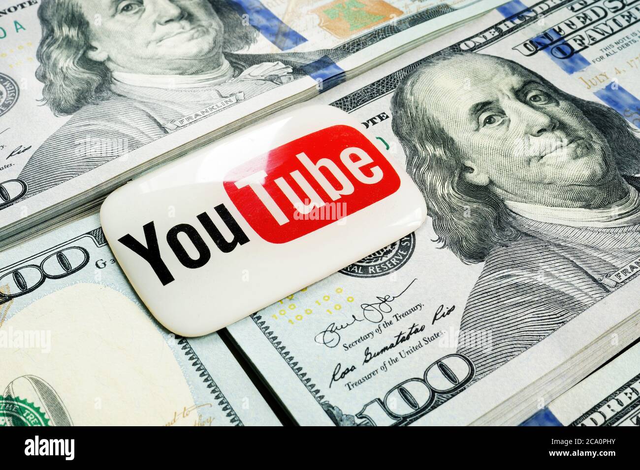 Kyiv, Ukraine - July 30, 2020: YouTube logo lies on the wads of money. Earnings by video blogging. Stock Photo