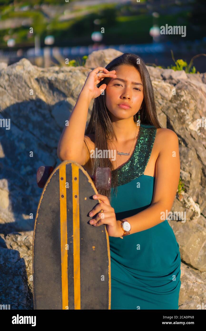 Young Latina in a green dress and a skate, with a seductive look Stock  Photo - Alamy