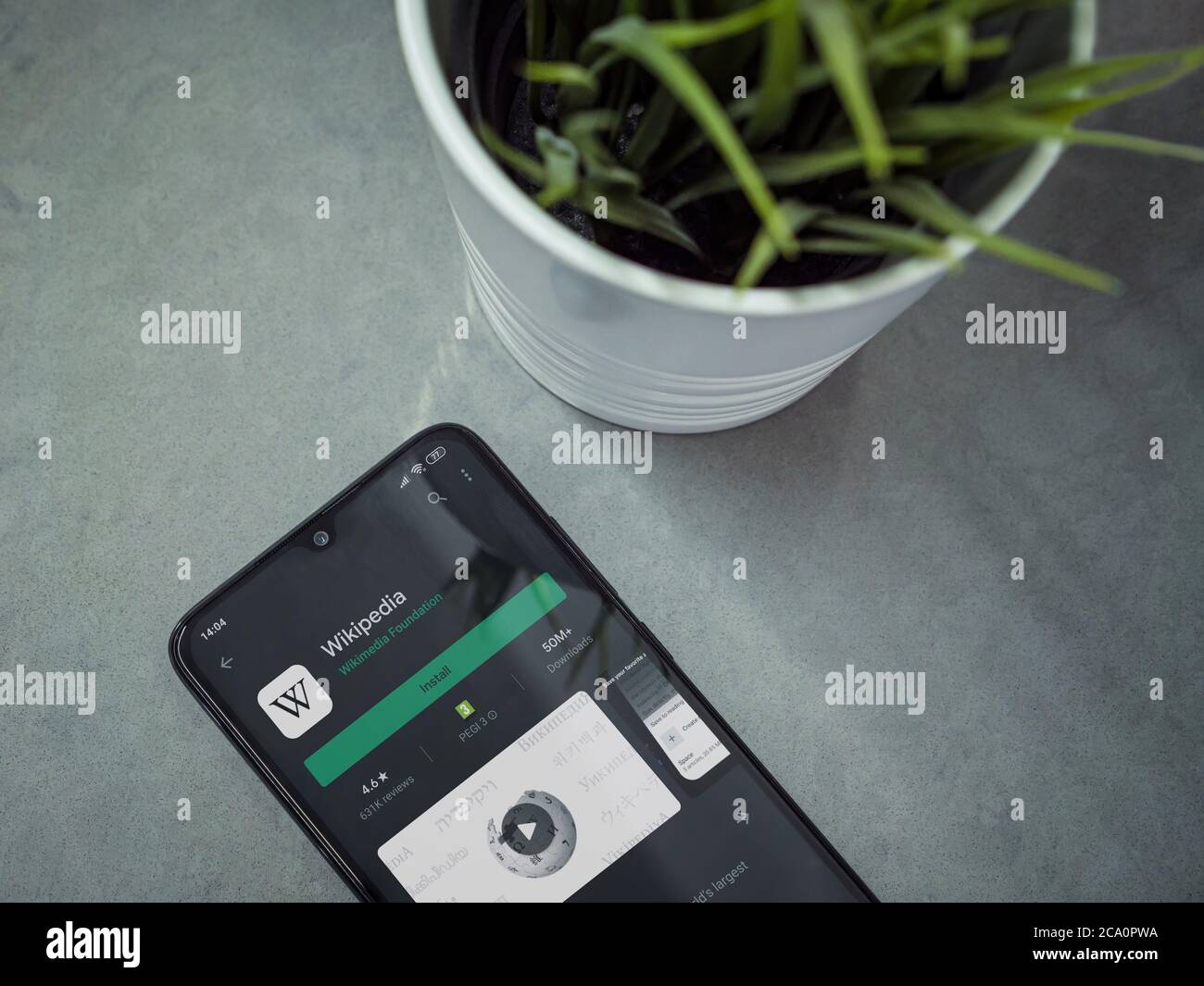 Lod, Israel - July 8, 2020: Modern minimalist office workspace with black mobile smartphone with Wikipedia app play store page on a marble background. Stock Photo