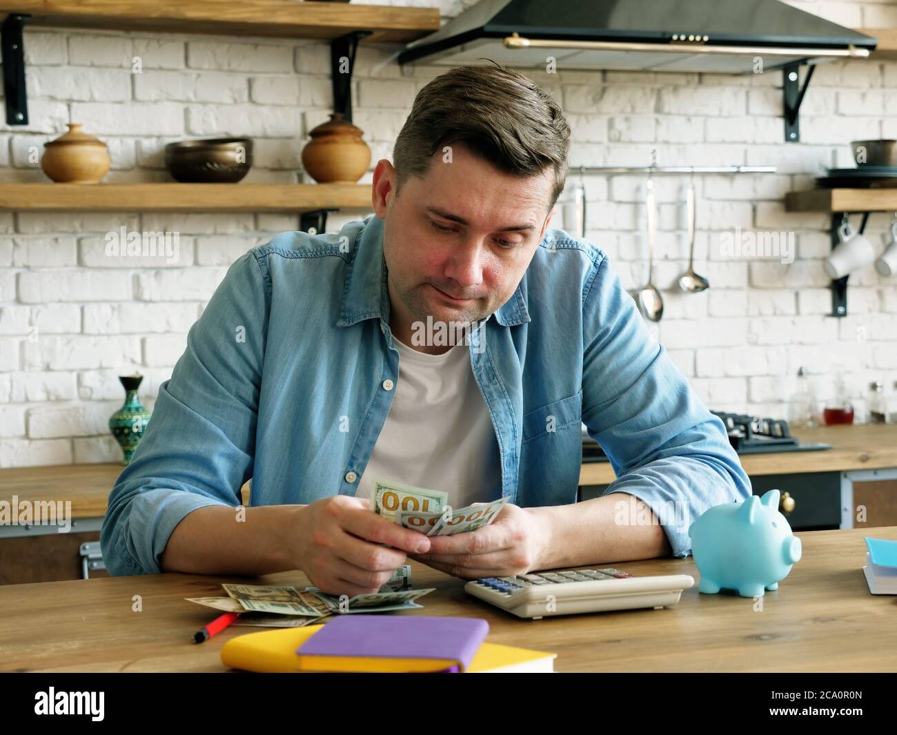 Problems with home finances. Man is counting money in the apartment. Stock Photo