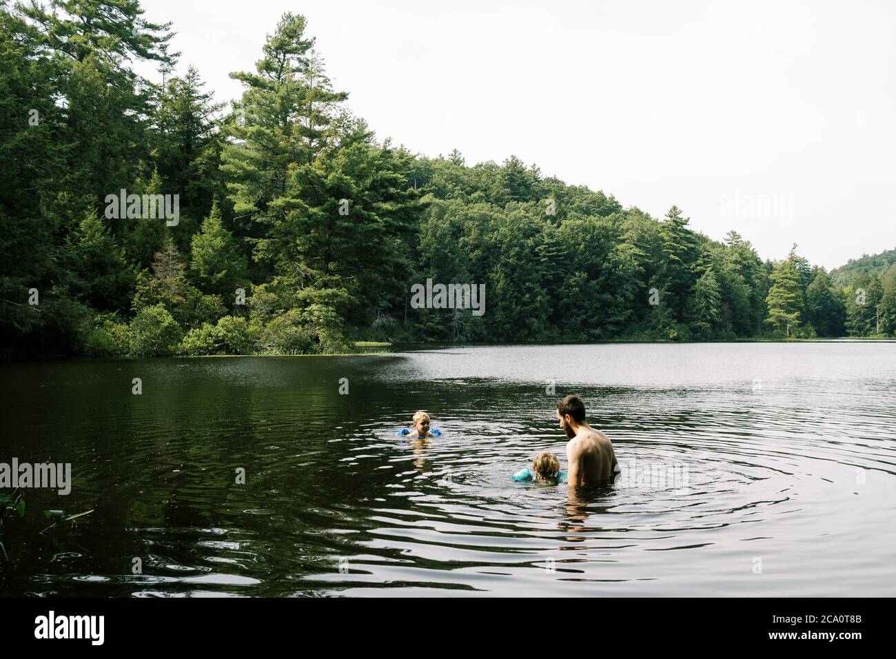 A father and his children cooling off in a hidden swimming hole Stock Photo
