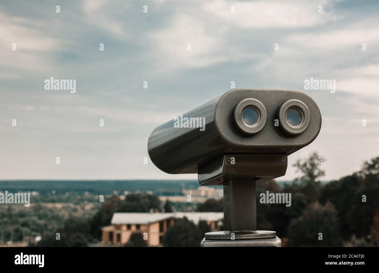 Touristic telescope overlooking city park. Metallic observation binoculars closeup with left copy space. Toned Stock Photo