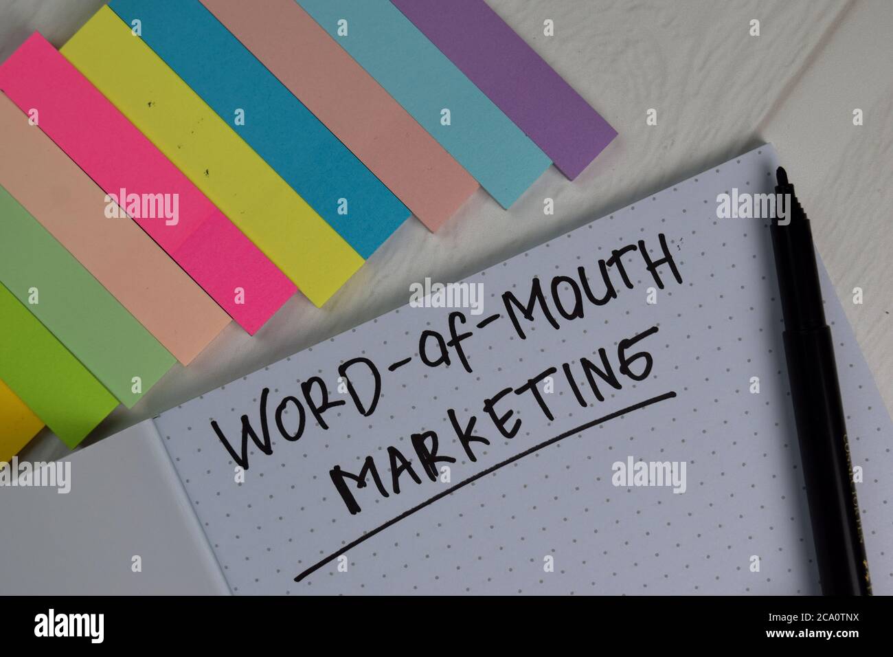 Word-of-Mouth Marketing write on a book isolated wooden table. Stock Photo