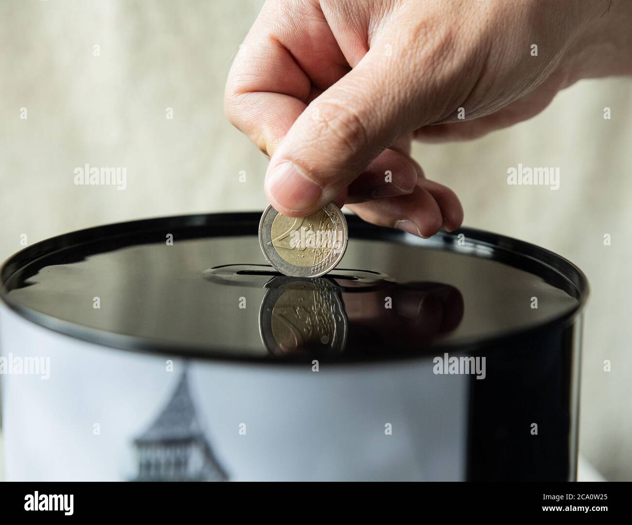 hand puts a 2 euro coin in a piggy bank Stock Photo - Alamy