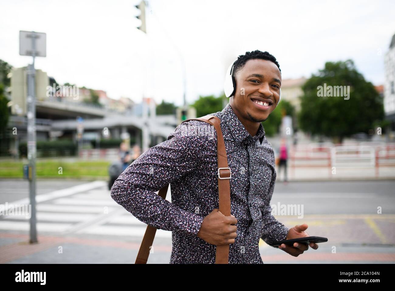 Cheerful young black man commuter outdoors in city, walking Stock Photo ...