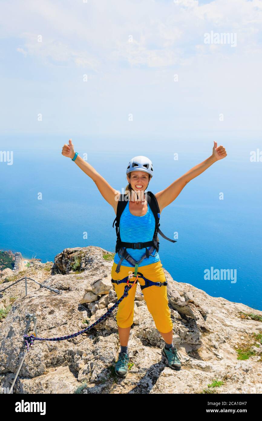 Happy young woman stand on mount top. Amazing sea landscape. Family travel adventure, hiking activity. Via ferrata tour with kids, exploring nature Stock Photo
