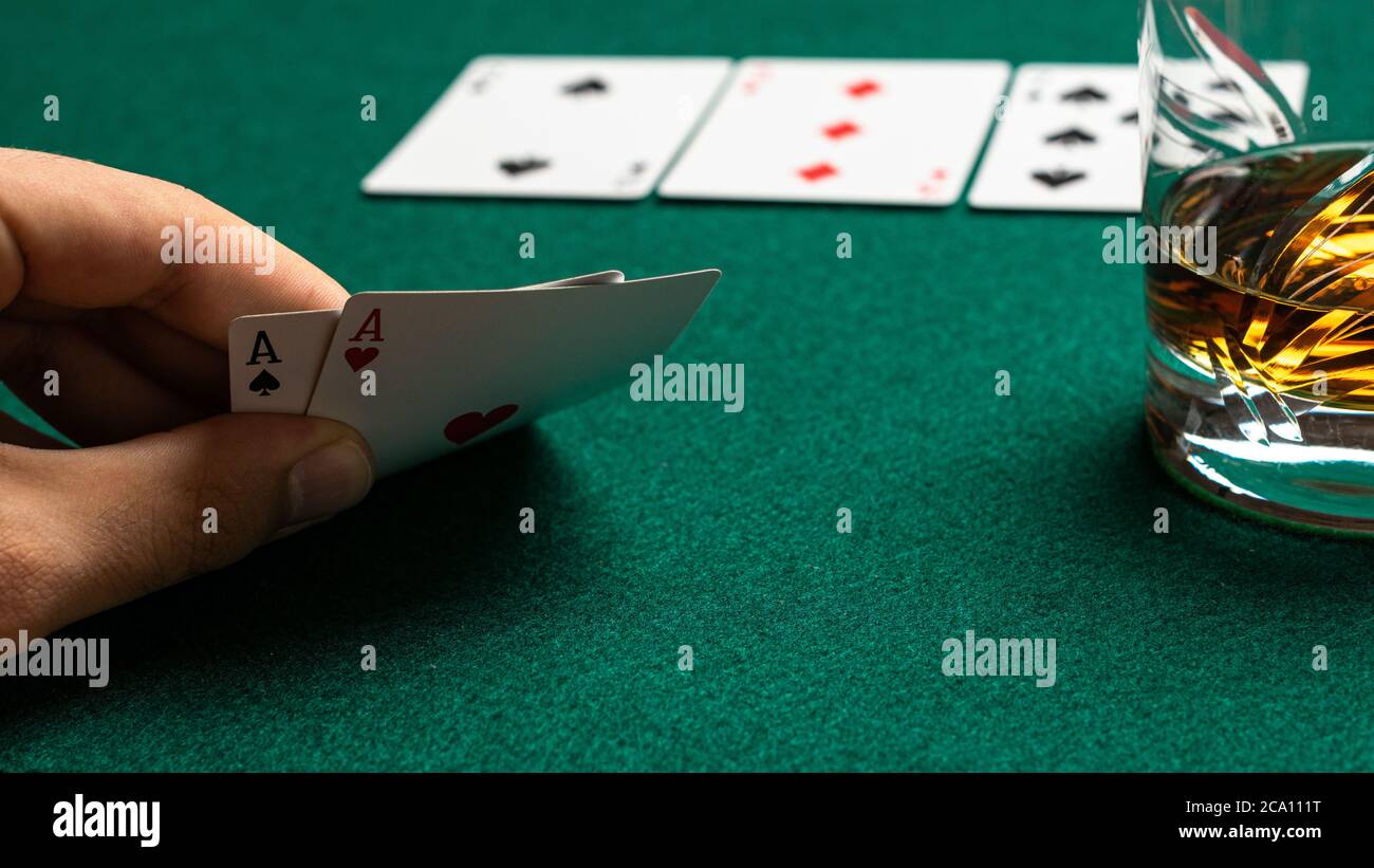 Poker player sees his two cards and drinks whiskey. Stock Photo