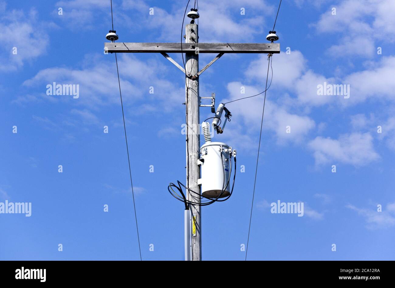 Overhead power line connection through fuse and transformer to residential underground power line. Stock Photo