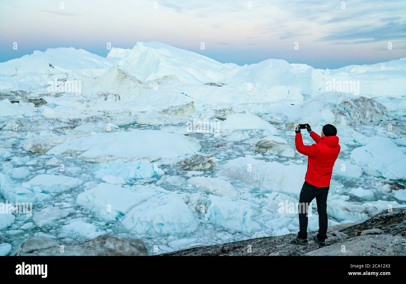 Travel in arctic landscape nature with icebergs. Greenland tourist man  explorer taking photo with phone of amazing Greenland icefjord in Ilulissat  Stock Photo - Alamy