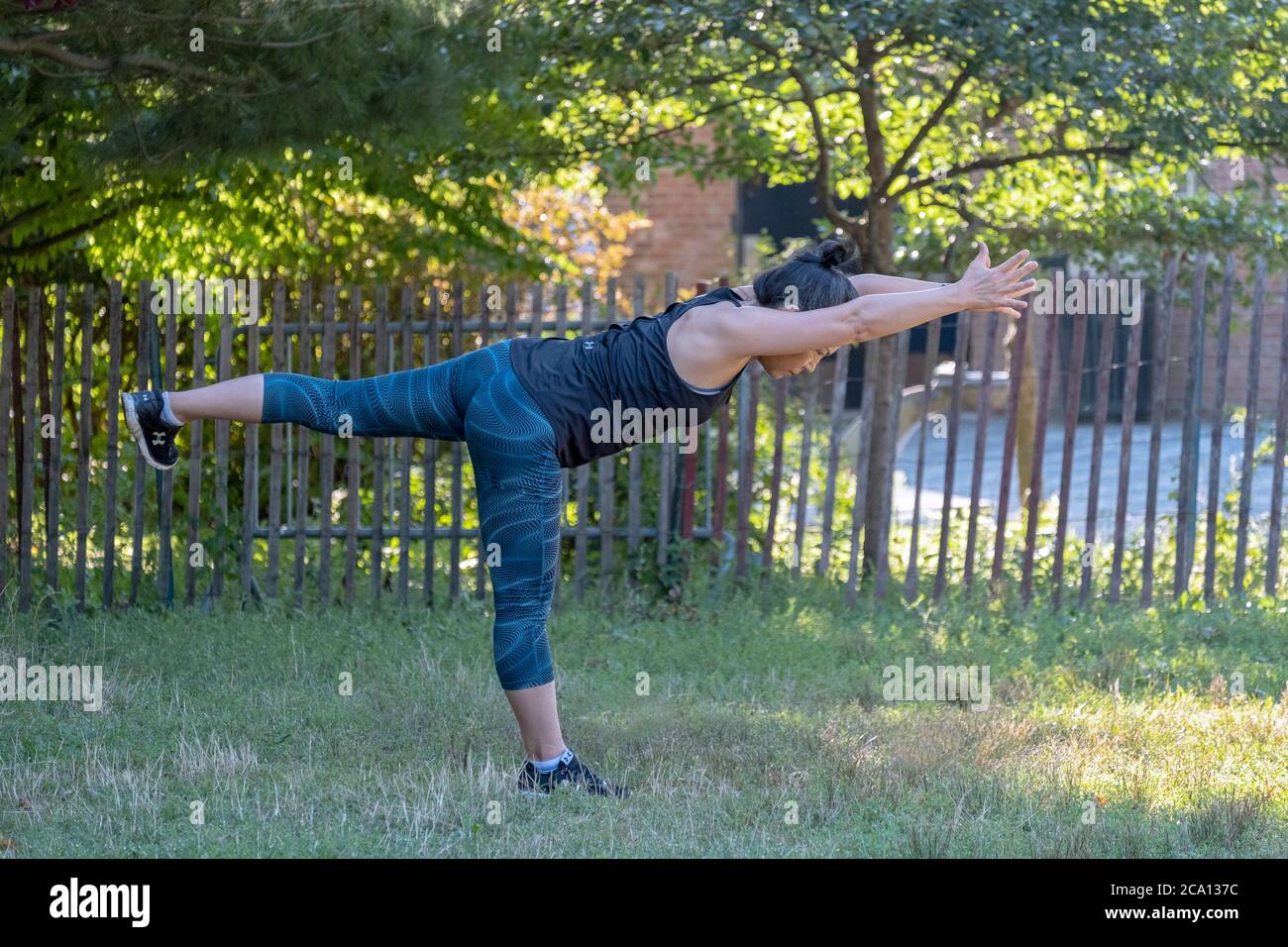 A fit middle aged Asian American woman does yoga stretching exercises