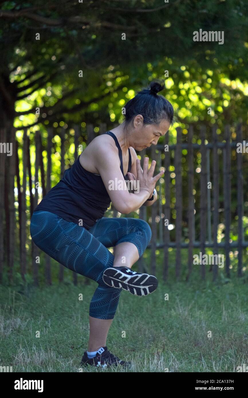 A fit middle aged Asian American woman does yoga stretching exercises