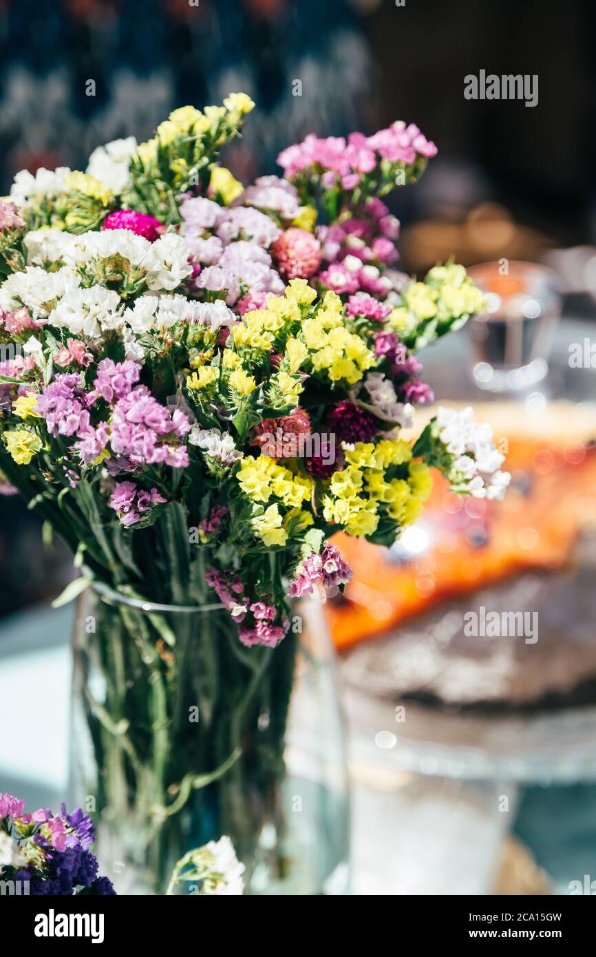A bouquet of fresh multicolored statice salem or limonium sinuatum flowers in violet, pink, white, yellow colors in a glass vase outdoors. Bunch of Stock Photo