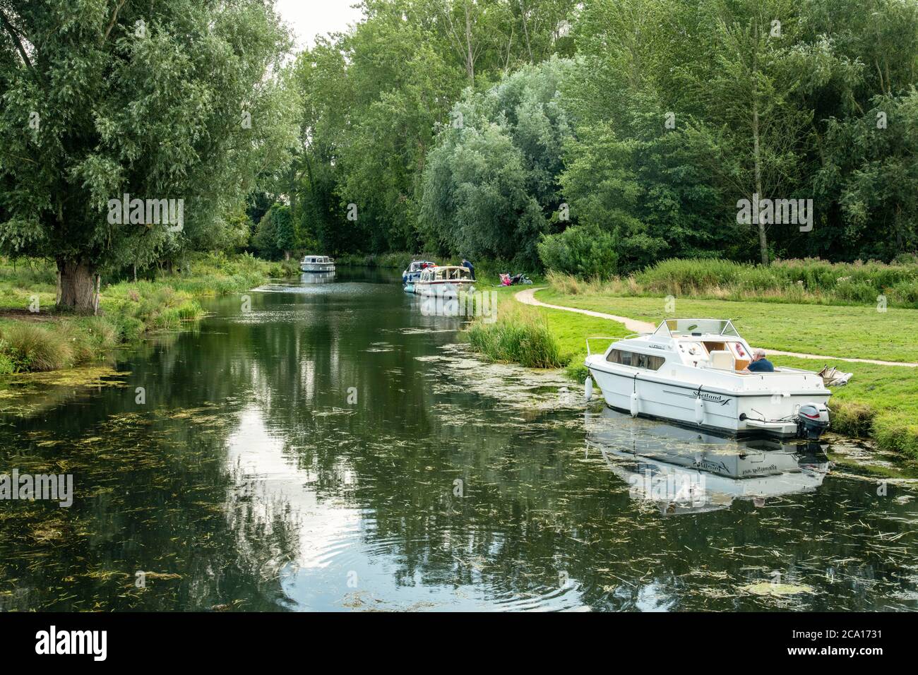 looking from Horstead Mill dam down the river bure on a summers day with boats moored to the river bank Stock Photo