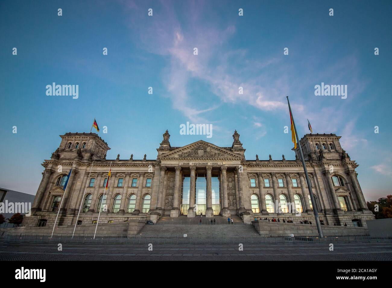 German Reichstag, the German parliament building in Berlin at sunset. Some german flags and one European waving. Politics and architecture concepts. Stock Photo