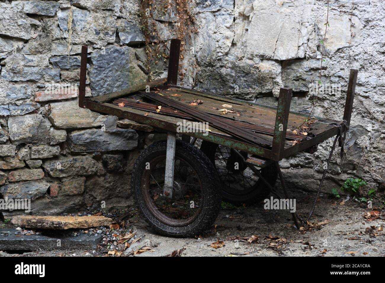 Rotten, rusty hand truck (carriage) in rainy weather in front of brick wall Stock Photo