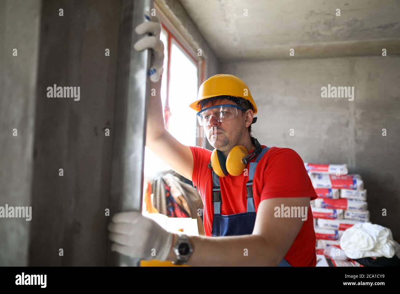Builder measures level wall at construction site Stock Photo